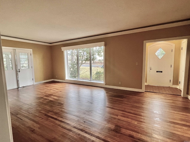 unfurnished living room featuring baseboards, wood finished floors, and crown molding