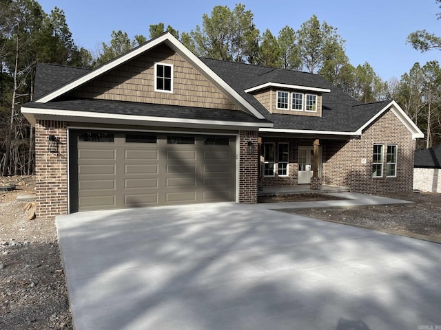 craftsman house featuring a garage, brick siding, driveway, and a shingled roof