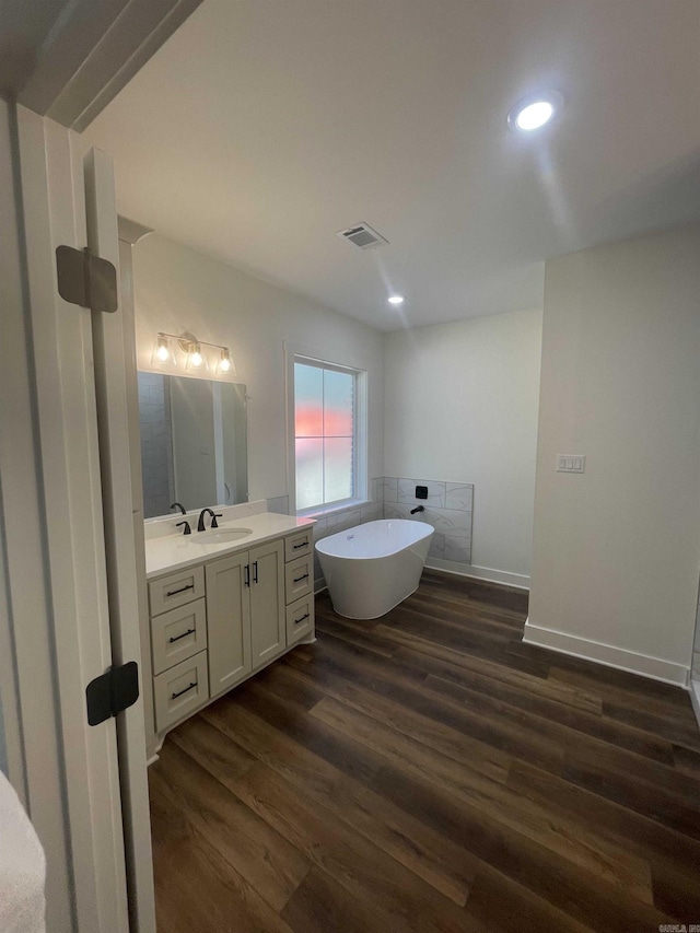 full bathroom featuring vanity, wood finished floors, visible vents, a soaking tub, and recessed lighting