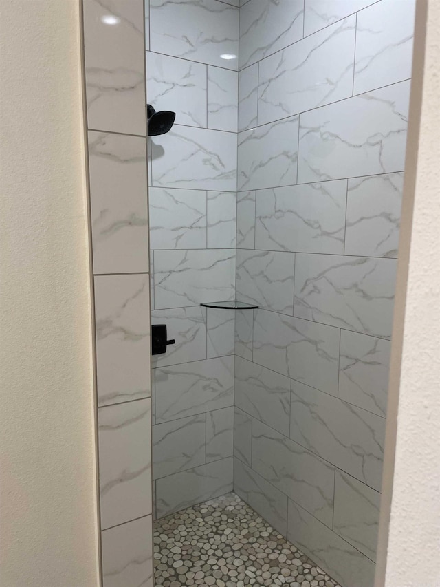 full bathroom featuring a textured wall and tiled shower