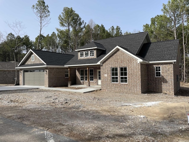 view of front of home with concrete driveway, an attached garage, brick siding, and roof with shingles