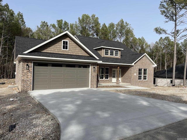 view of front of property featuring an attached garage, brick siding, driveway, and roof with shingles