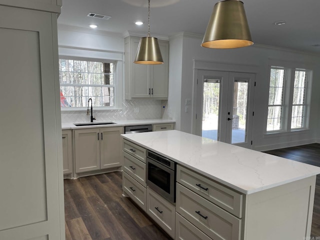 kitchen with stainless steel microwave, crown molding, visible vents, and a sink