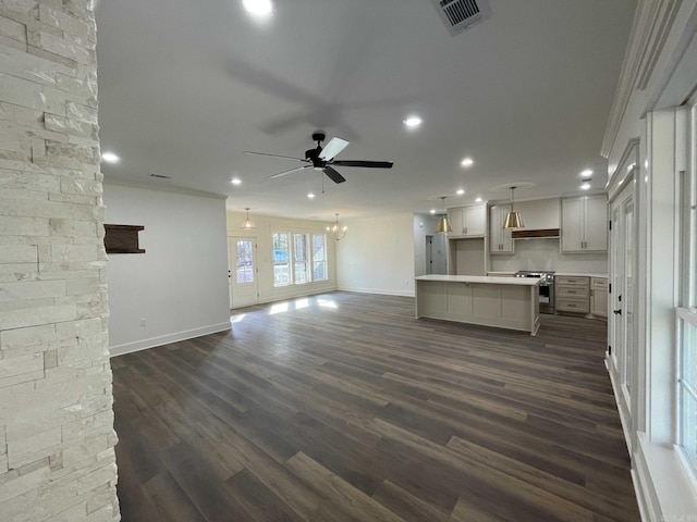 unfurnished living room featuring dark wood finished floors, visible vents, ceiling fan with notable chandelier, and crown molding