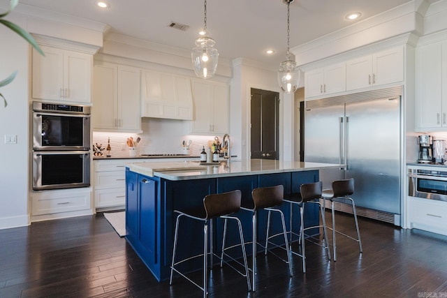 kitchen with a breakfast bar area, visible vents, ornamental molding, stainless steel appliances, and tasteful backsplash