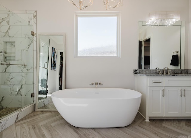 full bathroom with a marble finish shower, a freestanding bath, and vanity