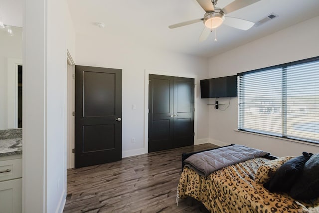 bedroom with a ceiling fan, baseboards, visible vents, dark wood-type flooring, and a closet