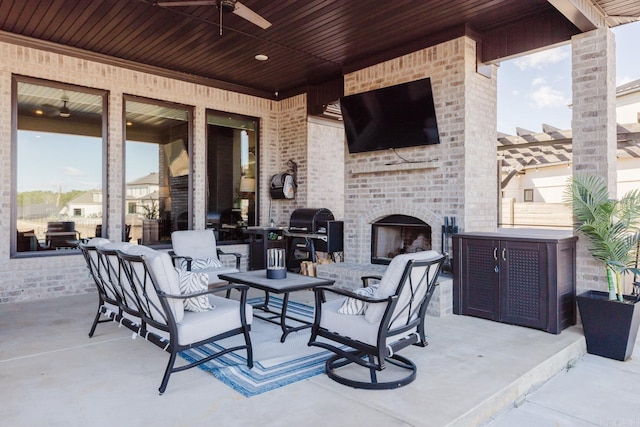 view of patio with area for grilling, a ceiling fan, and an outdoor brick fireplace