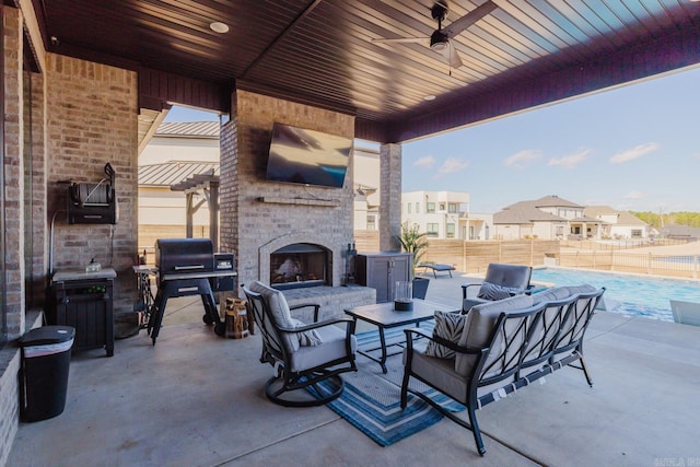 view of patio / terrace with a ceiling fan, an outdoor living space with a fireplace, fence, a grill, and a fenced in pool