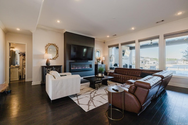 living room with visible vents, wood finished floors, baseboards, and ornamental molding