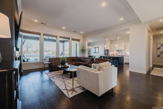 living area with visible vents, baseboards, dark wood-type flooring, and crown molding