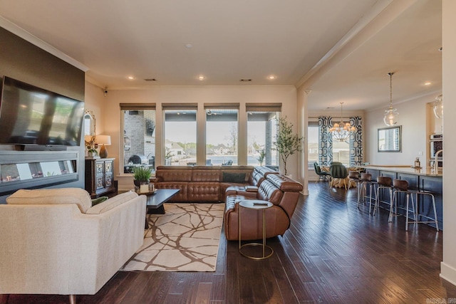 living room with recessed lighting, ornamental molding, an inviting chandelier, and hardwood / wood-style floors