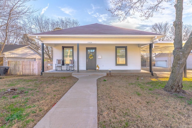 bungalow-style house with a porch, a front lawn, roof with shingles, and fence