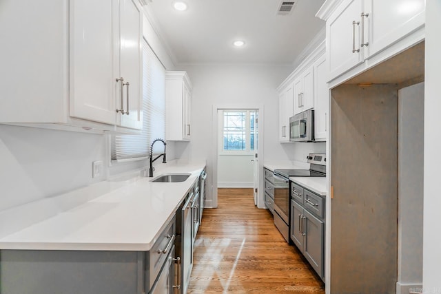 kitchen featuring visible vents, gray cabinetry, light countertops, appliances with stainless steel finishes, and a sink