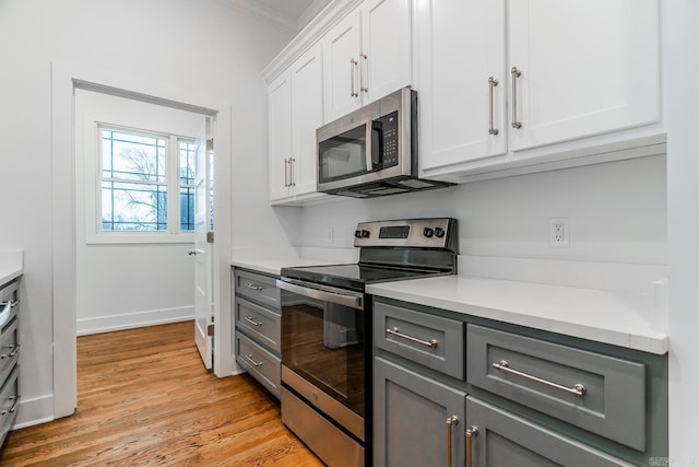 kitchen featuring stainless steel appliances, light wood-style floors, gray cabinets, and light countertops