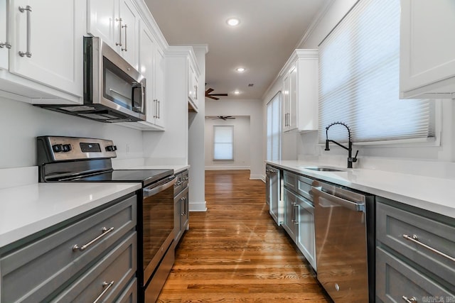 kitchen with appliances with stainless steel finishes, light countertops, gray cabinetry, and a sink