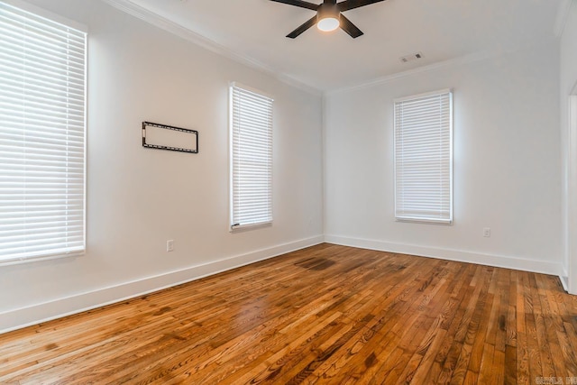 spare room with hardwood / wood-style floors, ornamental molding, visible vents, and ceiling fan