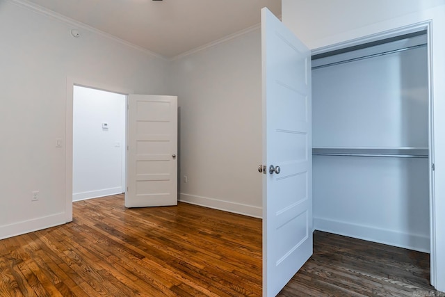 unfurnished bedroom featuring a closet, baseboards, wood finished floors, and crown molding