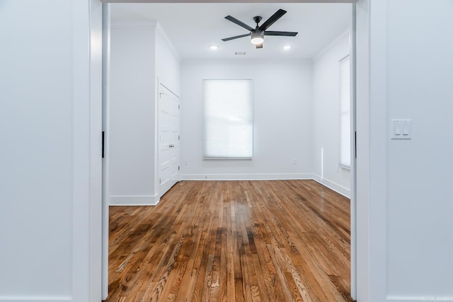 unfurnished room with a ceiling fan, plenty of natural light, wood finished floors, and ornamental molding