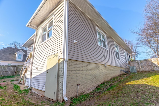 view of side of property with brick siding, central AC, and fence