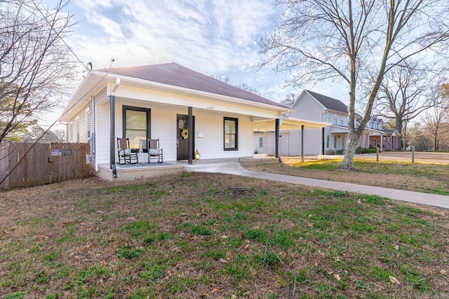 view of front of property featuring covered porch, a front yard, and fence