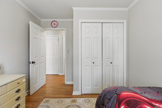 bedroom featuring crown molding, light wood-style floors, baseboards, and a closet