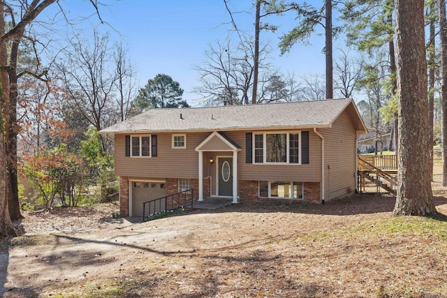 raised ranch featuring brick siding, an attached garage, and dirt driveway