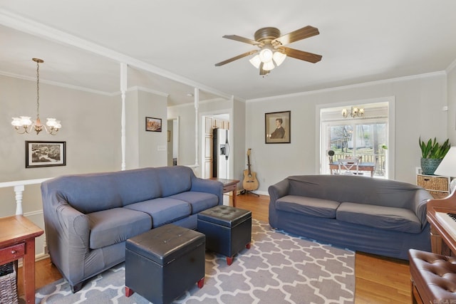 living room with ceiling fan with notable chandelier, baseboards, ornamental molding, and wood finished floors