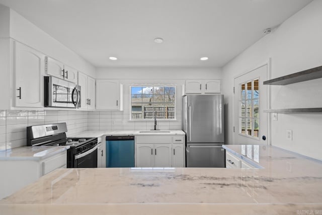 kitchen featuring backsplash, open shelves, stainless steel appliances, white cabinetry, and a sink