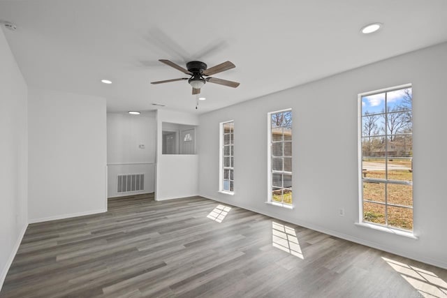 unfurnished living room featuring wood finished floors, a healthy amount of sunlight, visible vents, and ceiling fan