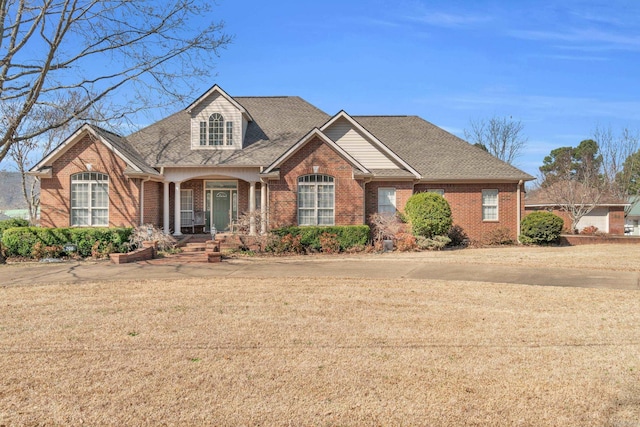 view of front of house with brick siding, a front lawn, and roof with shingles