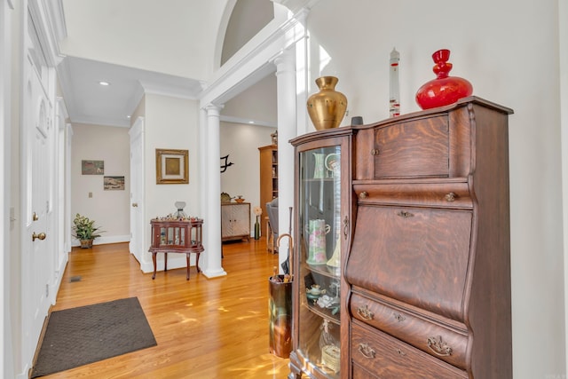 entryway with ornamental molding, baseboards, light wood-style floors, and decorative columns