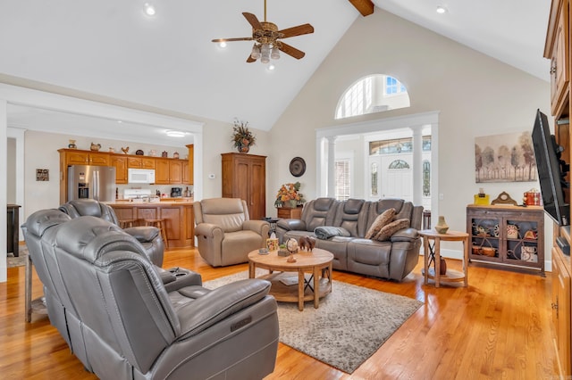 living area with beamed ceiling, light wood-style floors, ceiling fan, and high vaulted ceiling