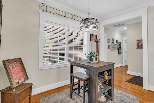 dining area with visible vents, wood finished floors, crown molding, baseboards, and a chandelier