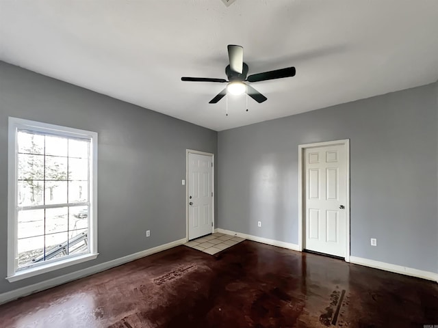 spare room featuring plenty of natural light, ceiling fan, and baseboards