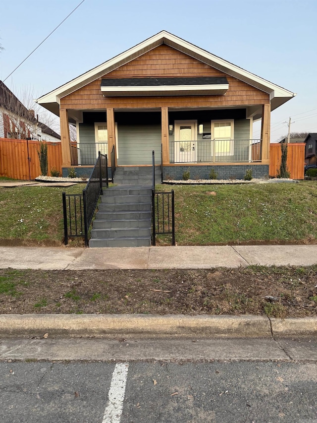 view of front facade featuring a porch, a front yard, and fence