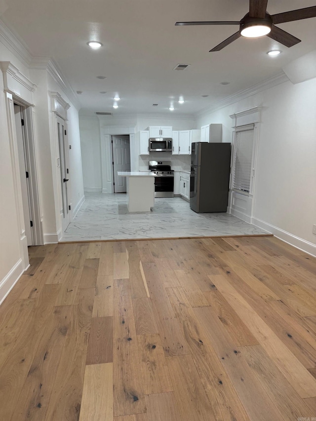 kitchen with crown molding, ceiling fan, open floor plan, light wood-style flooring, and appliances with stainless steel finishes