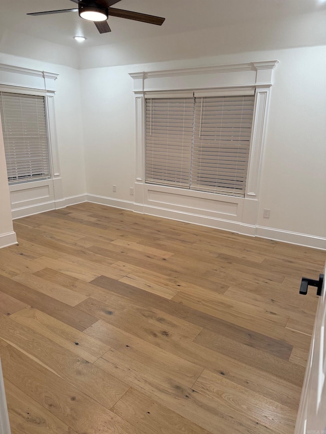 spare room featuring baseboards, hardwood / wood-style floors, and a ceiling fan