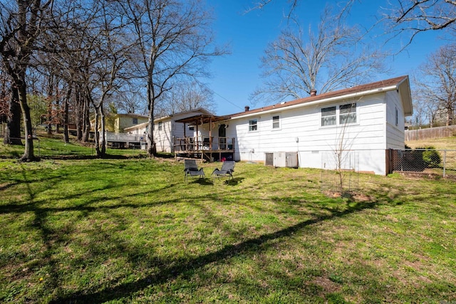 rear view of property with a yard, central air condition unit, and fence