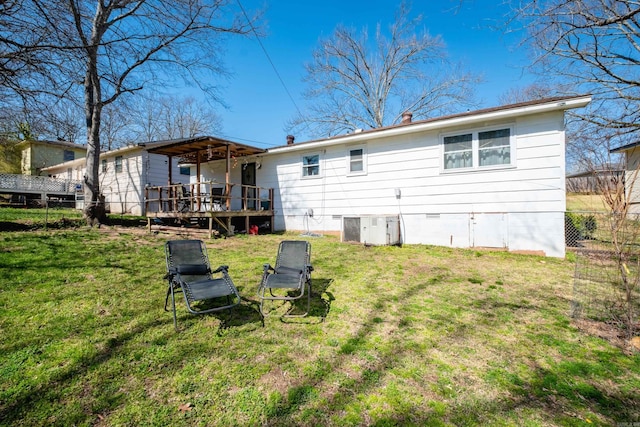 rear view of house featuring crawl space, a wooden deck, a yard, and fence