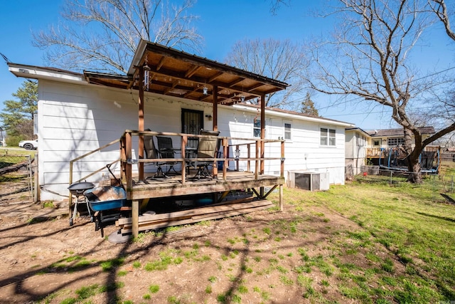 rear view of house featuring a yard, a deck, and fence