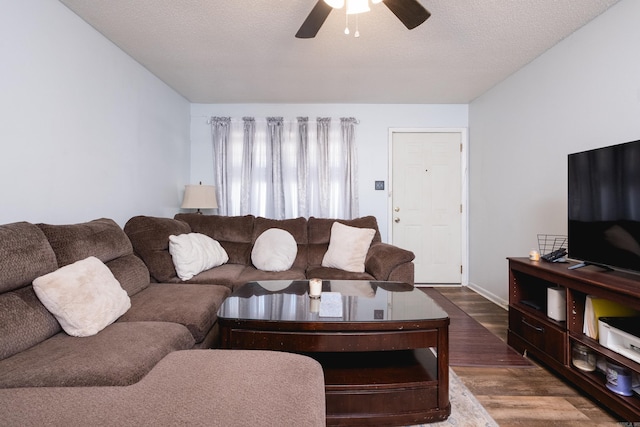 living area featuring a textured ceiling, dark wood-style floors, and a ceiling fan