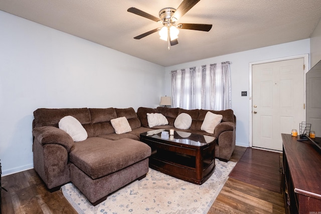 living room featuring dark wood finished floors, baseboards, a textured ceiling, and ceiling fan