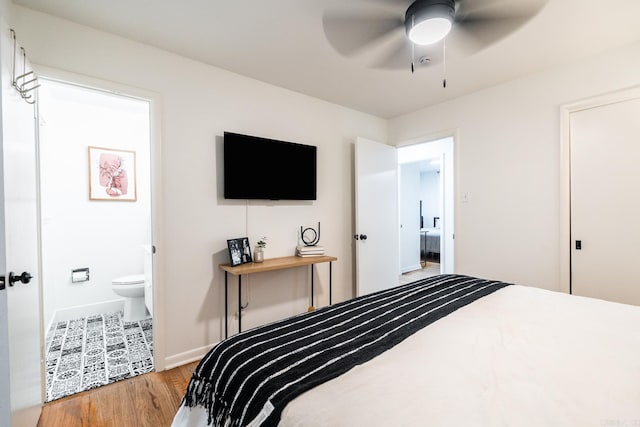 bedroom featuring a ceiling fan, ensuite bath, wood finished floors, and baseboards