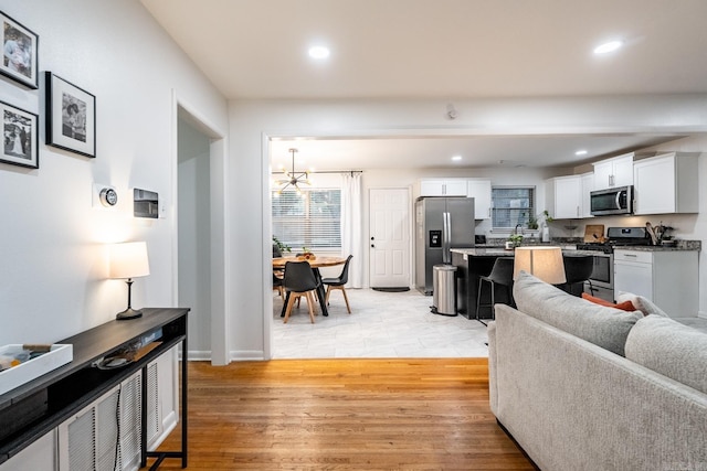 living area with recessed lighting, baseboards, light wood finished floors, and a chandelier