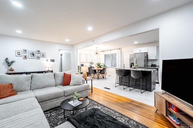 living room with recessed lighting, a chandelier, and light wood-style flooring