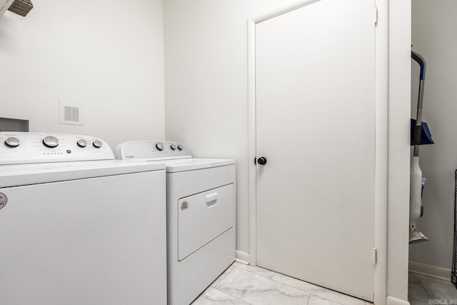 clothes washing area with baseboards, marble finish floor, washing machine and dryer, and laundry area