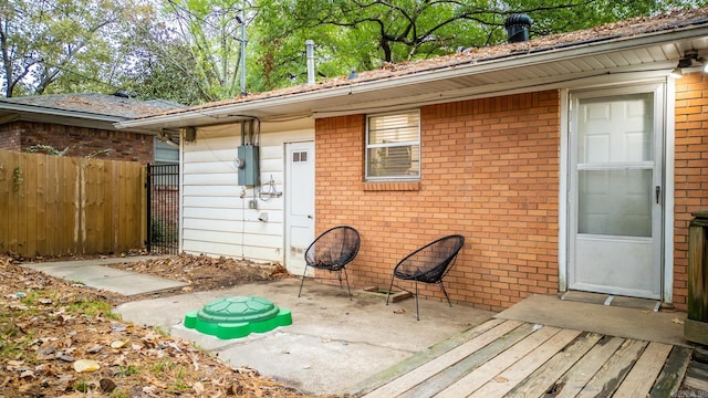 view of exterior entry featuring a patio, fence, and brick siding