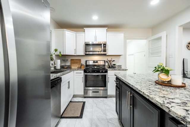 kitchen featuring marble finish floor, a sink, stainless steel appliances, white cabinets, and light stone countertops