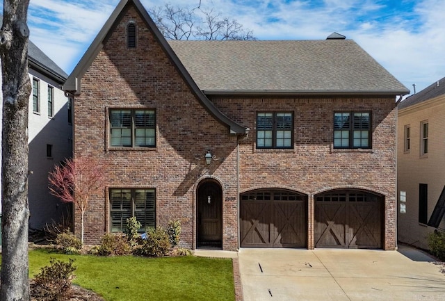 view of front of house featuring a front yard, driveway, roof with shingles, a garage, and brick siding